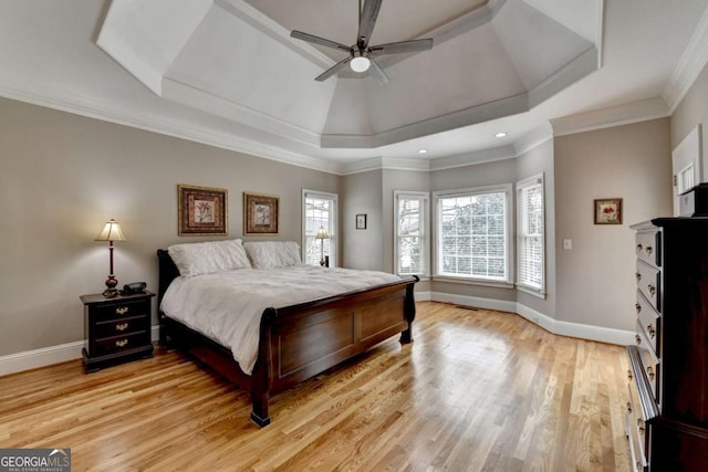 bedroom with crown molding, a tray ceiling, light hardwood / wood-style floors, and ceiling fan