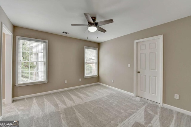 unfurnished room featuring plenty of natural light, light colored carpet, and ceiling fan