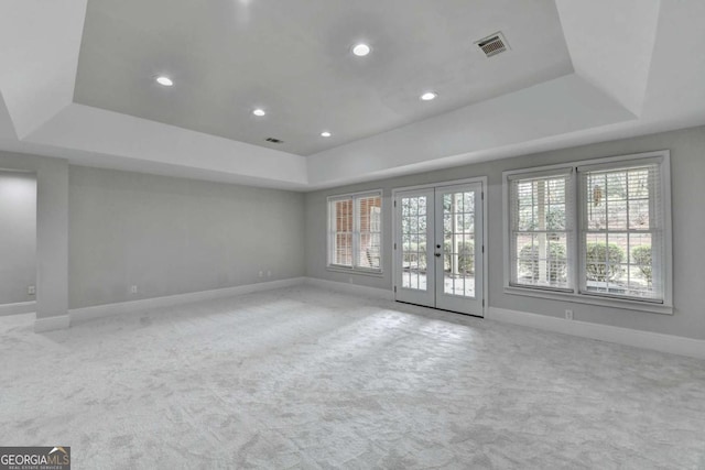 carpeted spare room with french doors and a tray ceiling