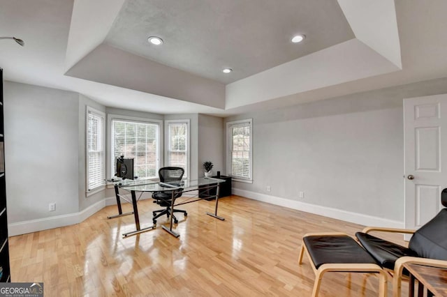 office featuring light hardwood / wood-style flooring and a tray ceiling