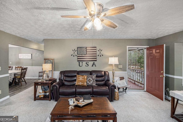 carpeted living room featuring a textured ceiling and ceiling fan