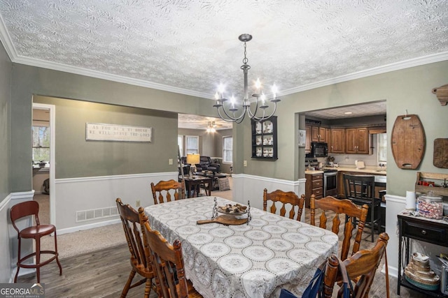 dining room featuring crown molding, hardwood / wood-style floors, a wealth of natural light, a textured ceiling, and a chandelier