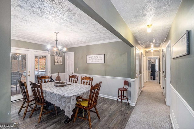 dining area with hardwood / wood-style floors, a notable chandelier, ornamental molding, a textured ceiling, and french doors