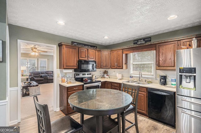 kitchen featuring a textured ceiling, sink, light hardwood / wood-style flooring, and black appliances