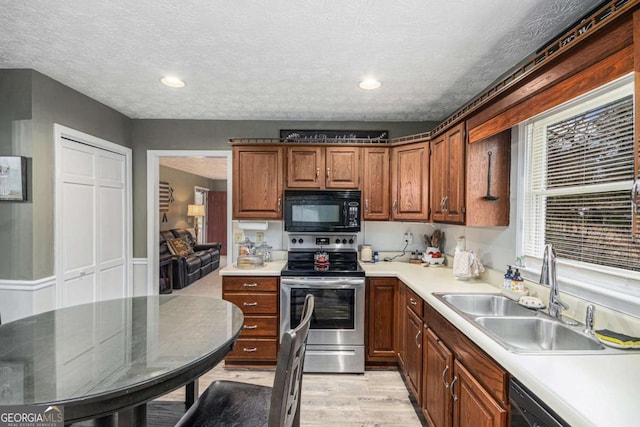 kitchen featuring light hardwood / wood-style floors, sink, a textured ceiling, and black appliances