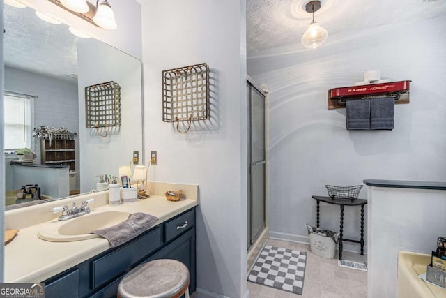 bathroom featuring vanity, a shower with shower door, and a textured ceiling