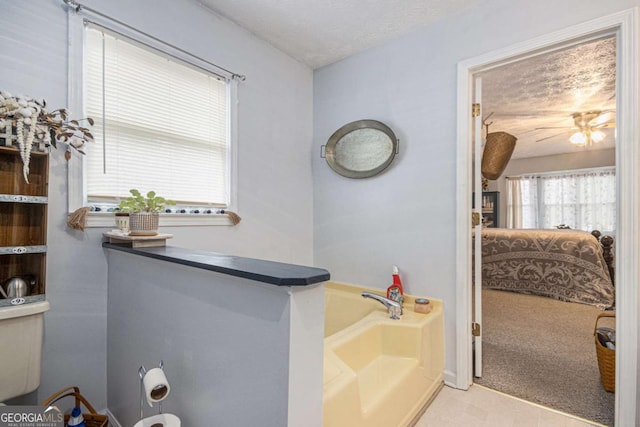 bathroom with a textured ceiling, toilet, and a bathing tub