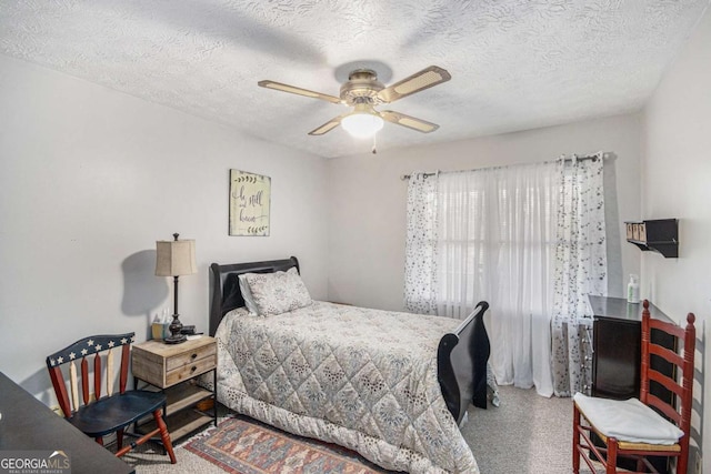 bedroom with ceiling fan, carpet floors, and a textured ceiling