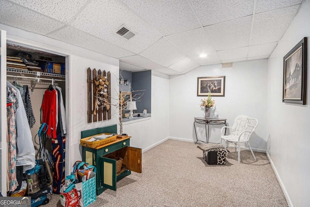 sitting room with a paneled ceiling and carpet