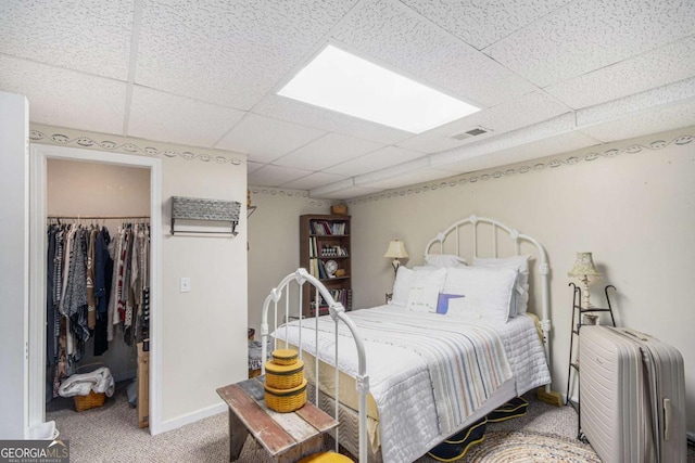 bedroom with radiator, carpet flooring, a spacious closet, a drop ceiling, and a closet