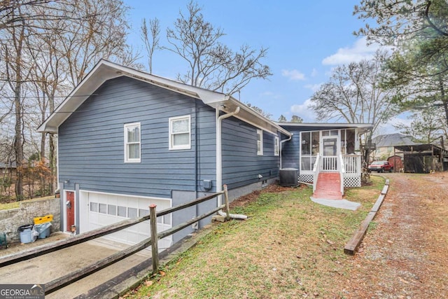 view of side of property featuring cooling unit, a yard, a garage, and a sunroom