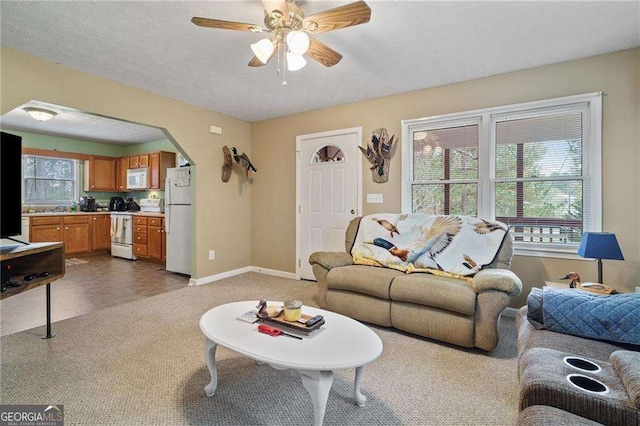 carpeted living room featuring ceiling fan and a textured ceiling