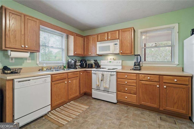 kitchen with sink, white appliances, and a textured ceiling