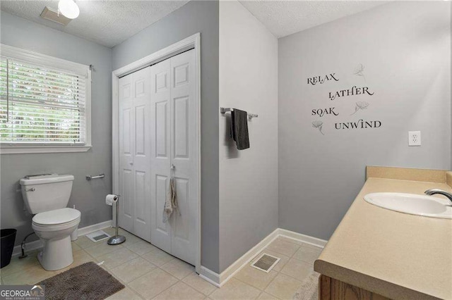 bathroom featuring vanity, tile patterned floors, a textured ceiling, and toilet