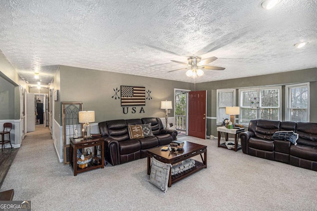 living room featuring ceiling fan, carpet flooring, and a textured ceiling