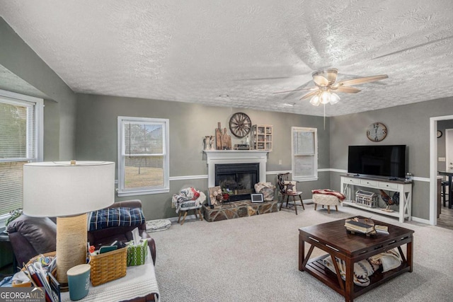 living room with a textured ceiling, ceiling fan, and carpet