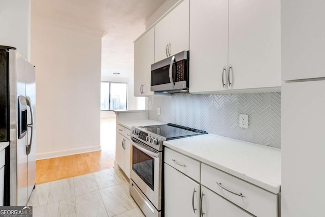 kitchen featuring stainless steel appliances, tasteful backsplash, light countertops, white cabinetry, and baseboards