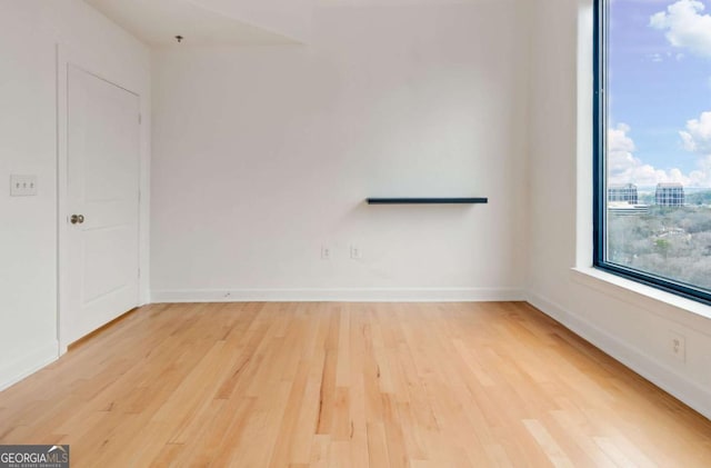 spare room featuring light wood-style floors and baseboards