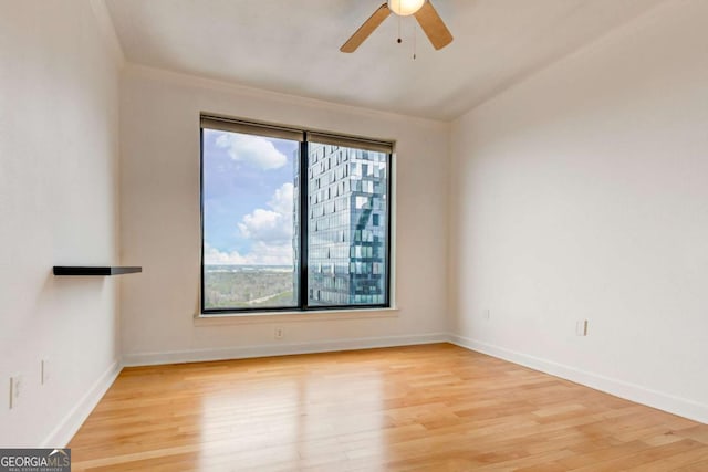 unfurnished room with light wood-style floors, plenty of natural light, baseboards, and a ceiling fan