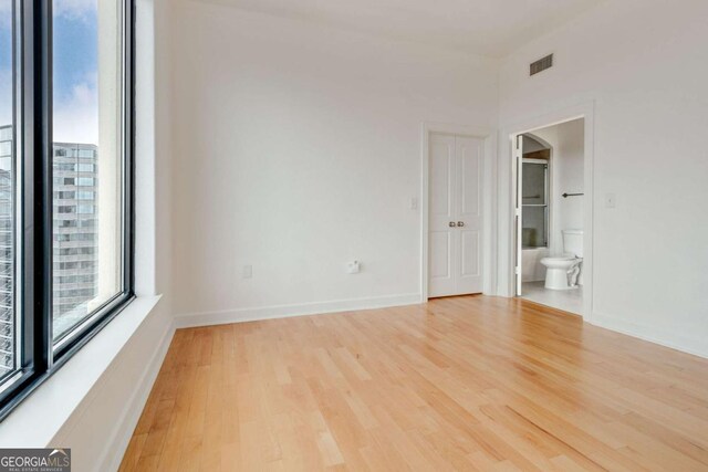 unfurnished room featuring baseboards, arched walkways, visible vents, and light wood-style floors