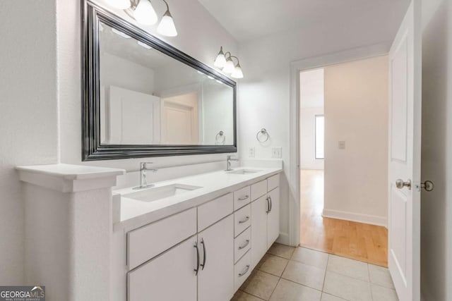 full bathroom with double vanity, tile patterned flooring, baseboards, and a sink