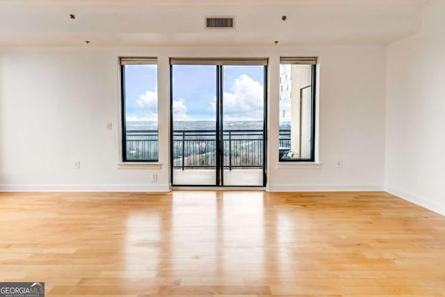 empty room with visible vents, light wood-style flooring, and baseboards