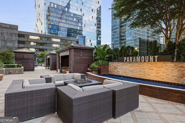 view of patio with an outbuilding, a view of city, a storage shed, and an outdoor living space with a fire pit