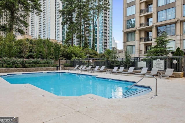 pool featuring a patio area, fence, and a city view