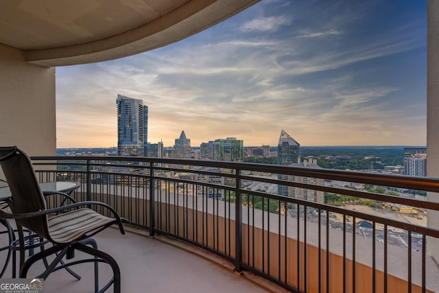 balcony at dusk featuring a view of city