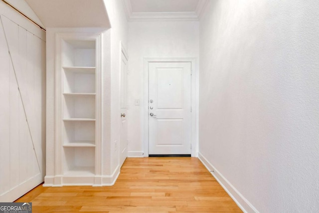 hallway featuring built in shelves, baseboards, ornamental molding, and light wood finished floors