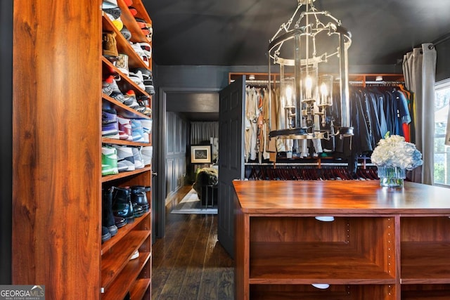 spacious closet with dark hardwood / wood-style floors and a notable chandelier