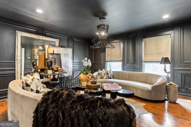 living room with a notable chandelier, recessed lighting, hardwood / wood-style flooring, and a decorative wall