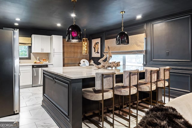 kitchen featuring pendant lighting, stainless steel appliances, a center island, and white cabinets