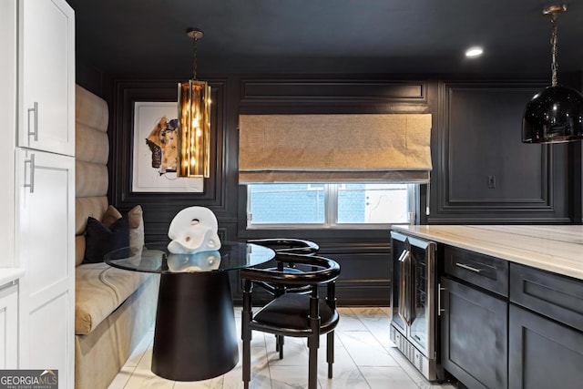 kitchen with wine cooler, hanging light fixtures, and light stone counters