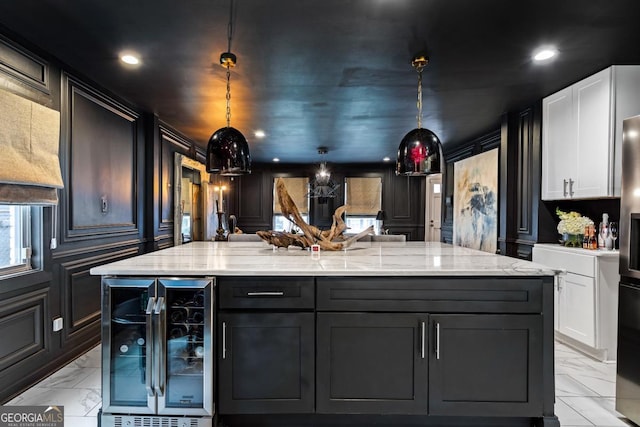 kitchen featuring white cabinetry, light stone counters, beverage cooler, and a kitchen island