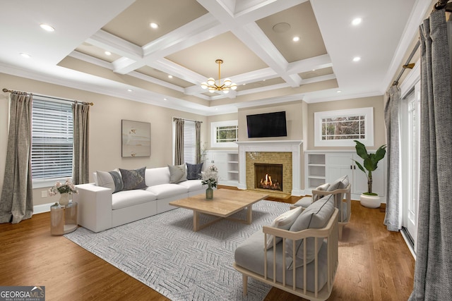 living area featuring coffered ceiling, a lit fireplace, and wood finished floors