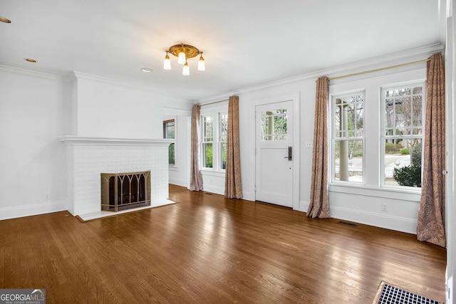 unfurnished living room with dark wood-type flooring, ornamental molding, and a fireplace