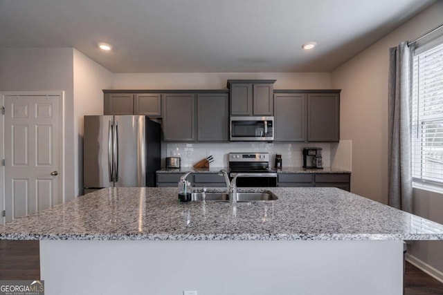 kitchen featuring light stone countertops, an island with sink, and appliances with stainless steel finishes