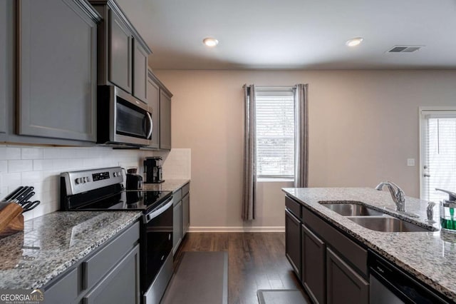 kitchen featuring light stone counters, sink, backsplash, and stainless steel appliances