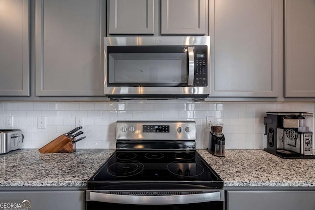 kitchen featuring gray cabinetry, decorative backsplash, and stainless steel appliances