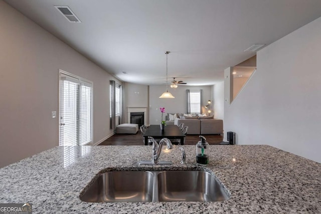 kitchen with sink, hardwood / wood-style flooring, light stone countertops, and ceiling fan