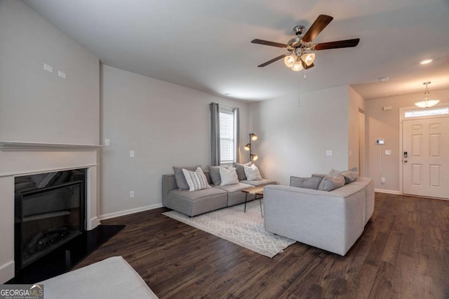 living room with dark wood-type flooring and ceiling fan