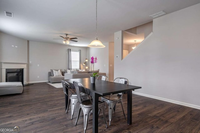 dining area featuring a premium fireplace, dark hardwood / wood-style floors, and ceiling fan