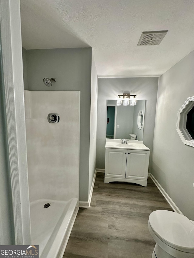 bathroom with walk in shower, toilet, a textured ceiling, vanity, and hardwood / wood-style floors