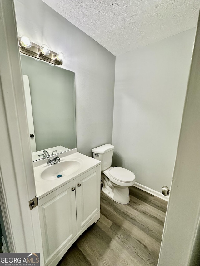 bathroom with vanity, toilet, hardwood / wood-style floors, and a textured ceiling