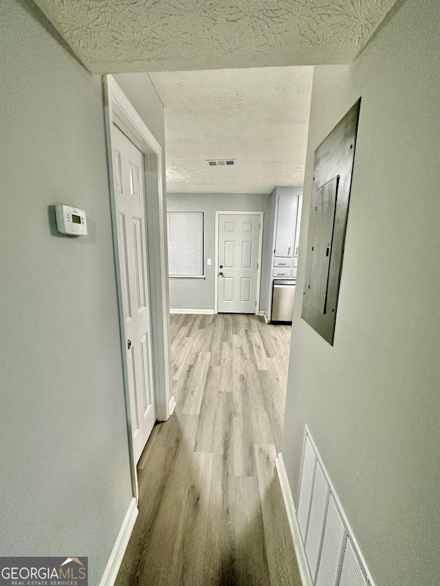 hall with light hardwood / wood-style floors and a textured ceiling