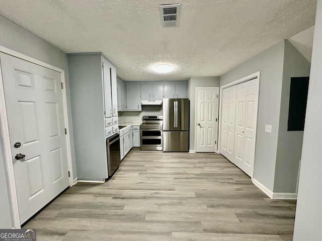 kitchen with appliances with stainless steel finishes, a textured ceiling, and light wood-type flooring