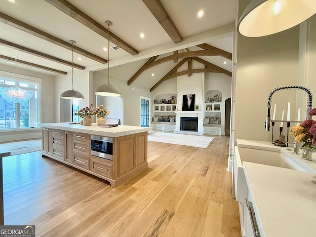 kitchen with open floor plan, light countertops, hanging light fixtures, a center island, and light brown cabinetry