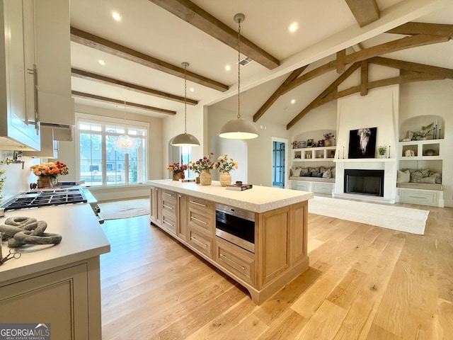 kitchen with light wood-style flooring, a kitchen island, open floor plan, light countertops, and decorative light fixtures