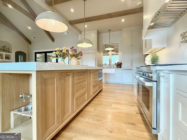 kitchen featuring white cabinets, decorative light fixtures, extractor fan, light countertops, and light wood-style floors